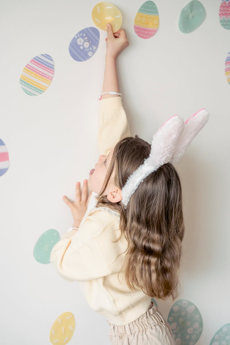 Adorable Girl Applying Colorful Easter Stickers On Wall