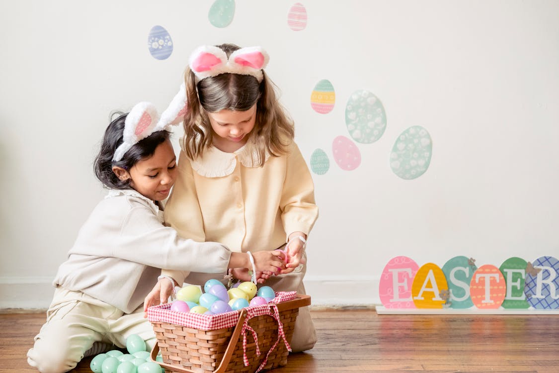 Free Cute diverse girls playing with colorful Easter eggs Stock Photo