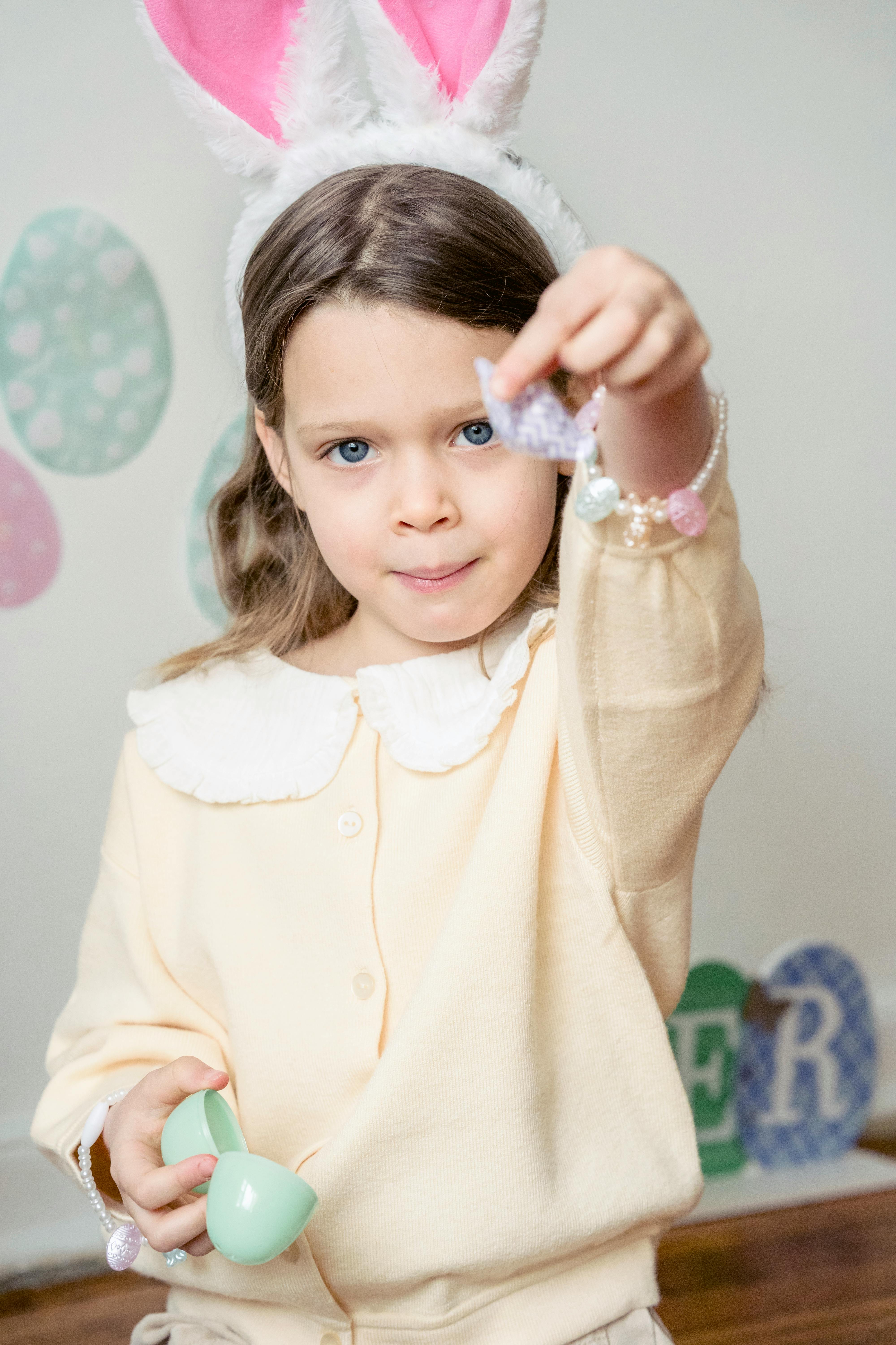 adorable kid holding candy and plastic egg during easter celebration