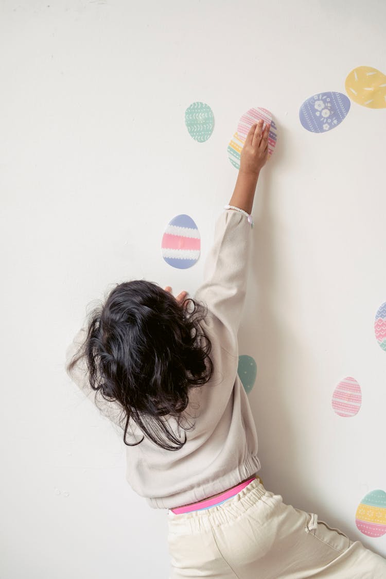 Anonymous Kid Decorating Wall With Colorful Egg Stickers