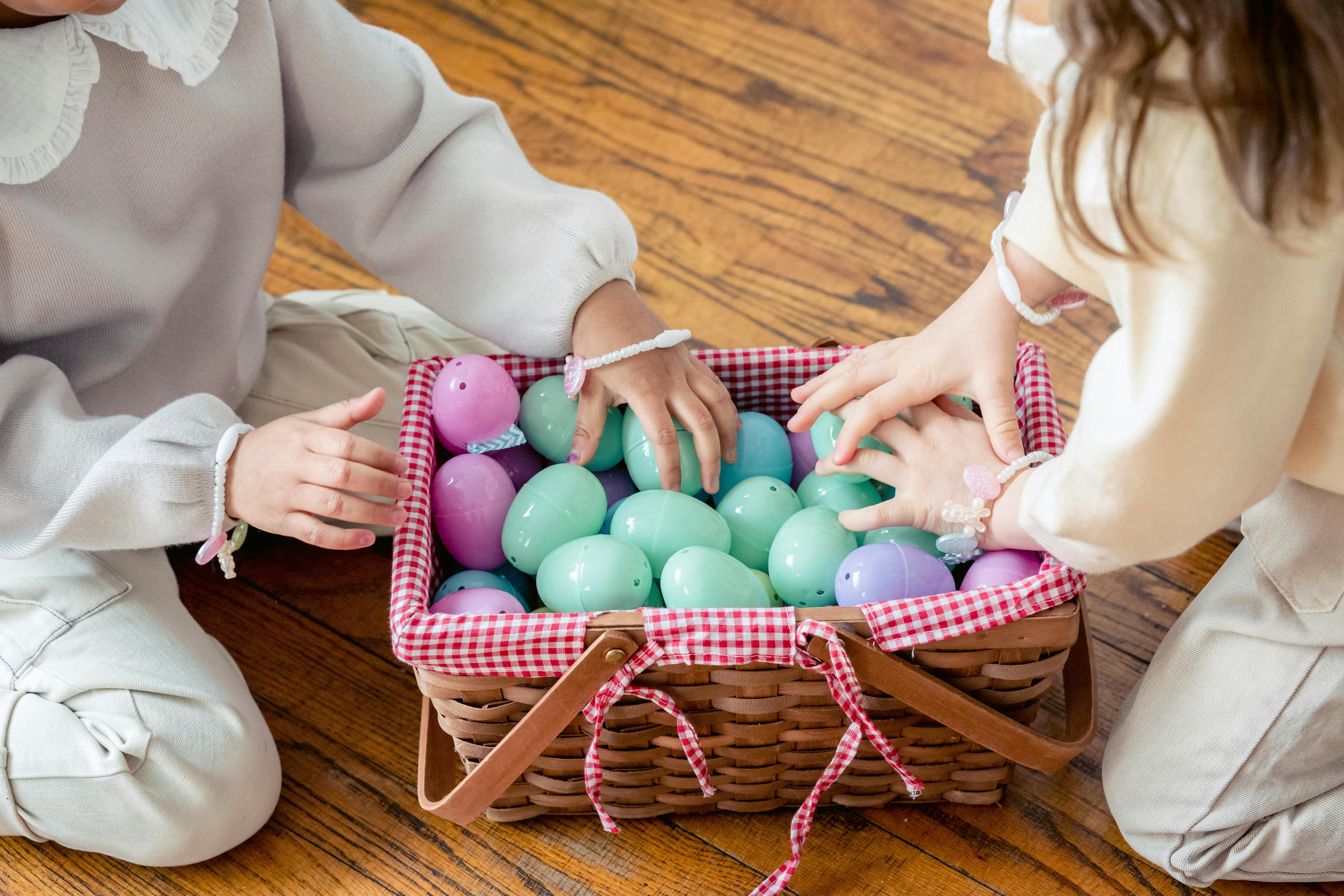 crop faceless kids playing with artificial easter eggs on floor at home