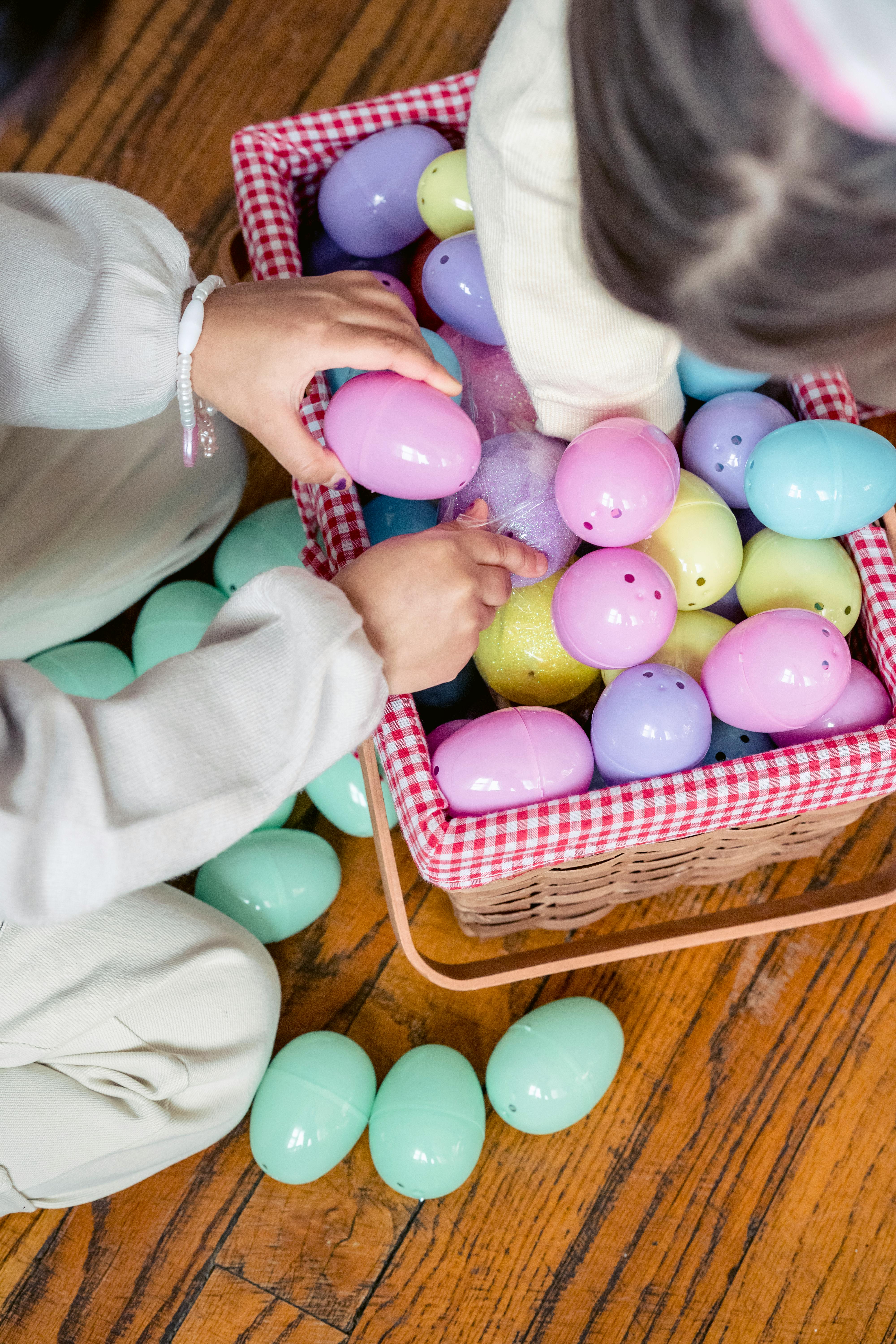 girl collecting plastic eggs into wicker basket on floor