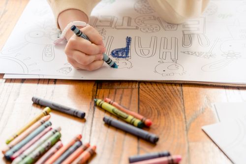Free From above of crop anonymous preschool girl drawing with crayons on postcard on floor in daylight Stock Photo