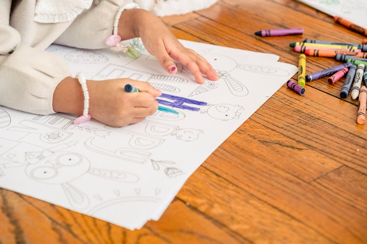 Girl Coloring Picture With Bright Crayons On Wooden Floor