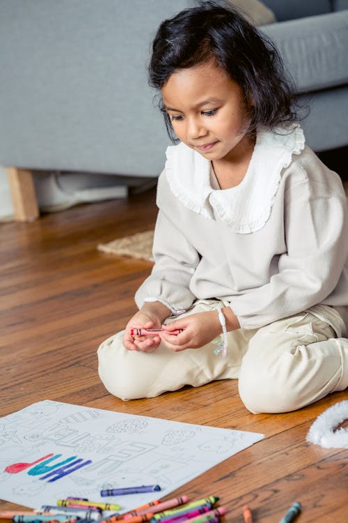 Free Focused ethnic girl sitting on floor while paining at home Stock Photo