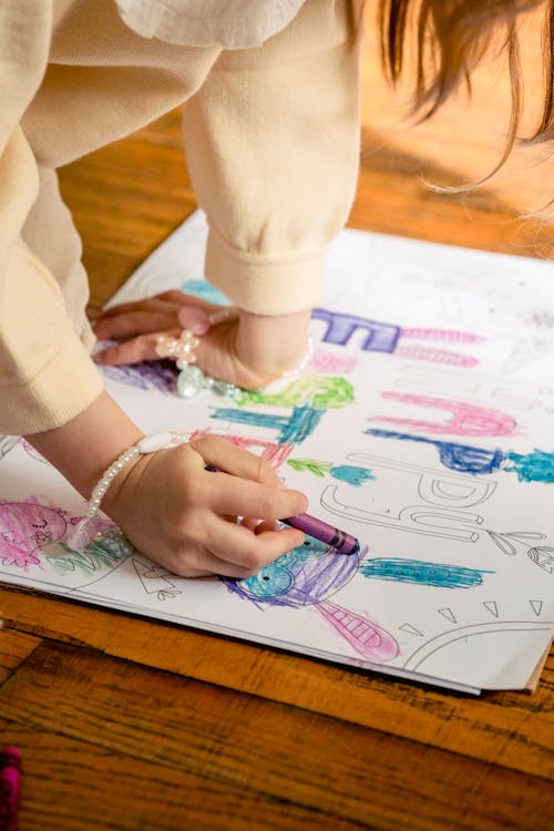 Free Crop anonymous girl in casual clothes drawing in coloring book at home in daytime Stock Photo