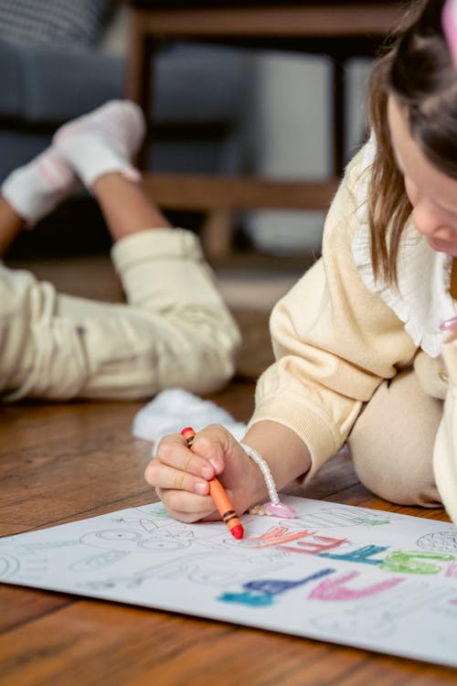 Free Little girl drawing in coloring book in living room Stock Photo