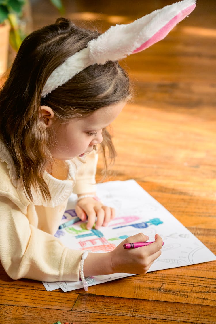 Girl Coloring Paper With Easter Eggs And Letters On Floor