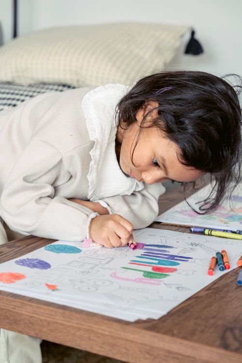 Free Side view of concentrated Hispanic girl drawing colorful placard for Easter celebration with chalk pencils Stock Photo