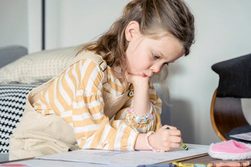 Free Focused girl coloring picture with crayon Stock Photo