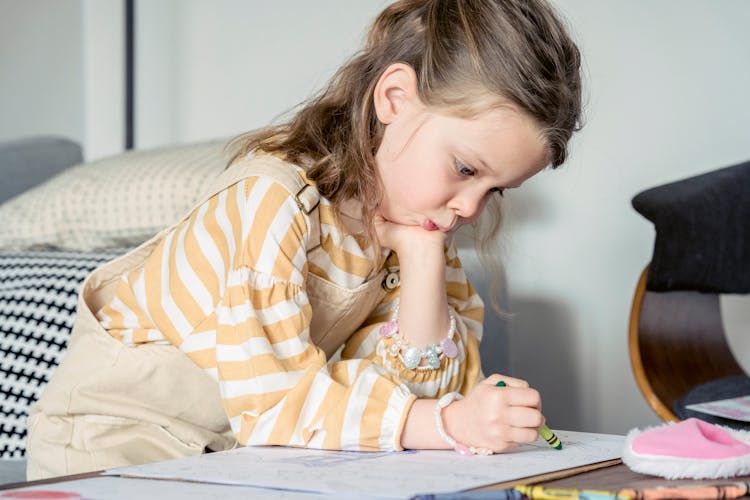 Focused Girl Coloring Picture With Crayon