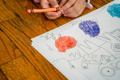 Free High angle of crop anonymous child at wooden table with painted chicken and eggs on paper for Easter holiday Stock Photo