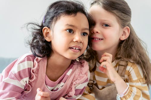 Free Smiling little Hispanic girl with brown eyes near cute best friend with long hair Stock Photo