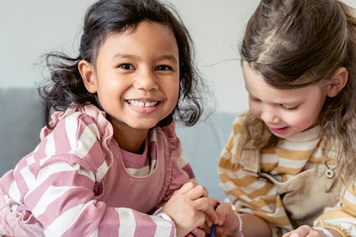 Happy diverse girls painting with crayons together