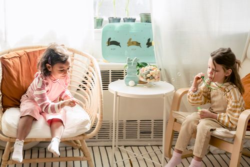 Free High angle of multiethnic friends sitting together in armchairs and blowing soap bubbles sitting in bedroom with Easter decor Stock Photo