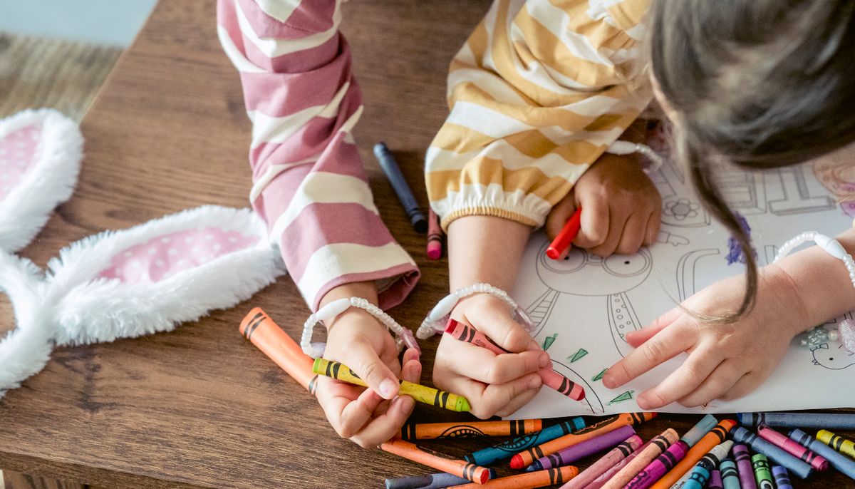 Sisters painting and coloring a little chick picture together with crayons