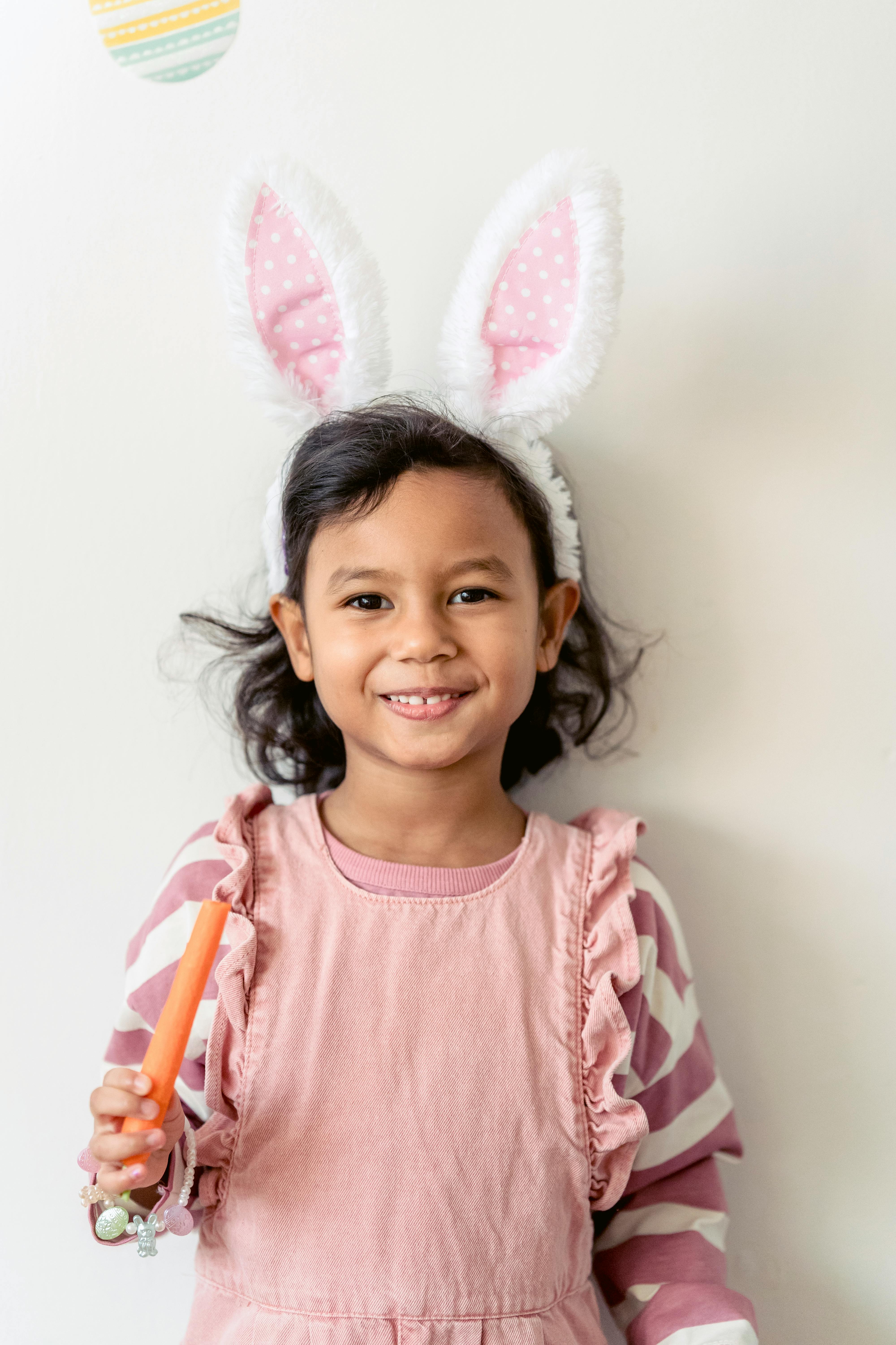 smiling ethnic girl in bunny ears with carrot