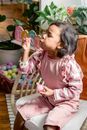 A Girl Sitting on a Chair while Blowing the Bubbles