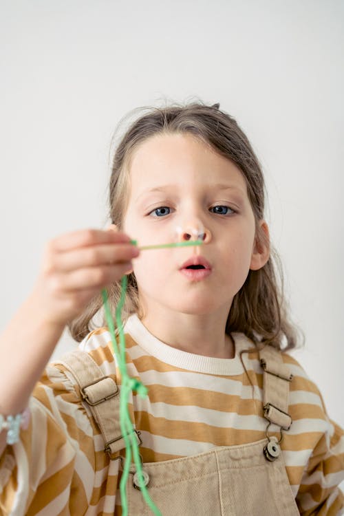 Girl in Brown and White Stripe Long Sleeve Shirt Blowing a Soap Bubble