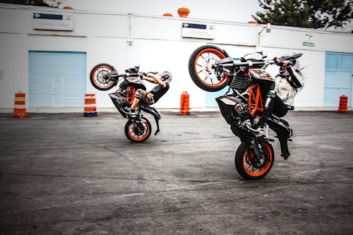 Two Men Riding Orange-and-black Sports Bikes While Doing Exhibition