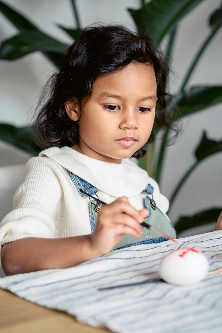 Girl Painting Egg On Table