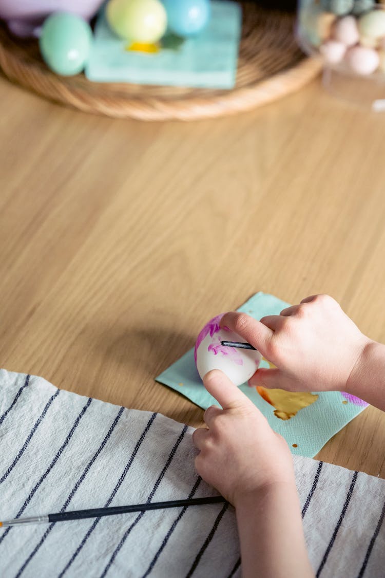 Child Painting Easter Egg On Table