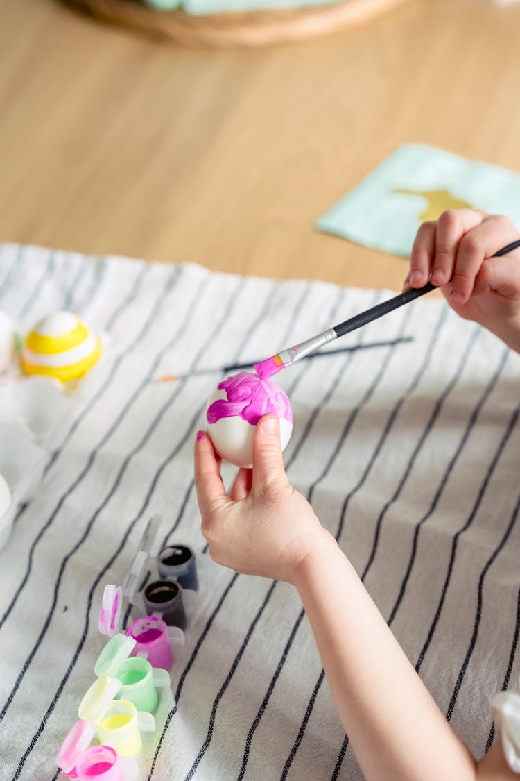 Close Up Of Childs Hands Painting Easter Egg In Purple