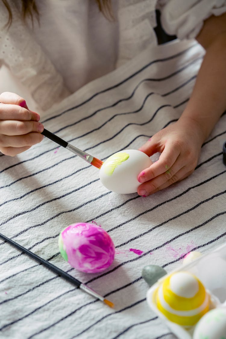 Unrecognizable Kid Painting Eggs With Paintbrush