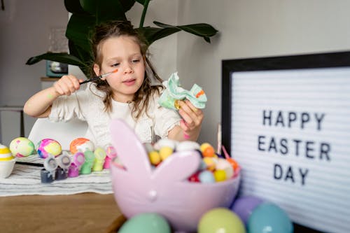 Free Cute girl painting eggs at table with signboard Stock Photo