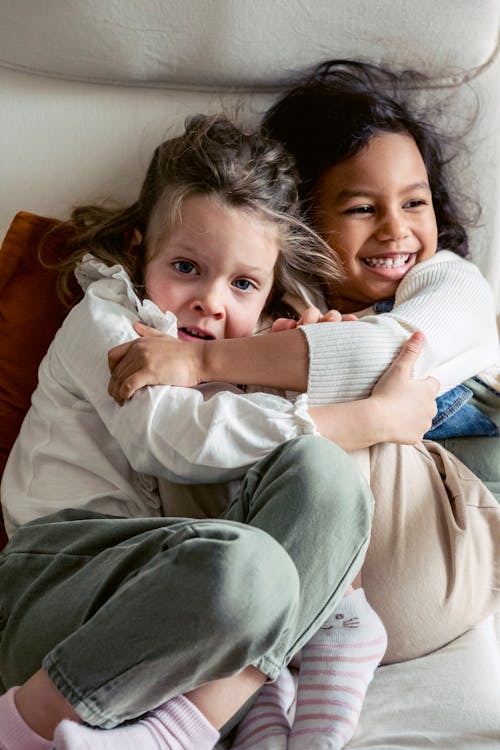 Cheerful diverse kids cuddling in room