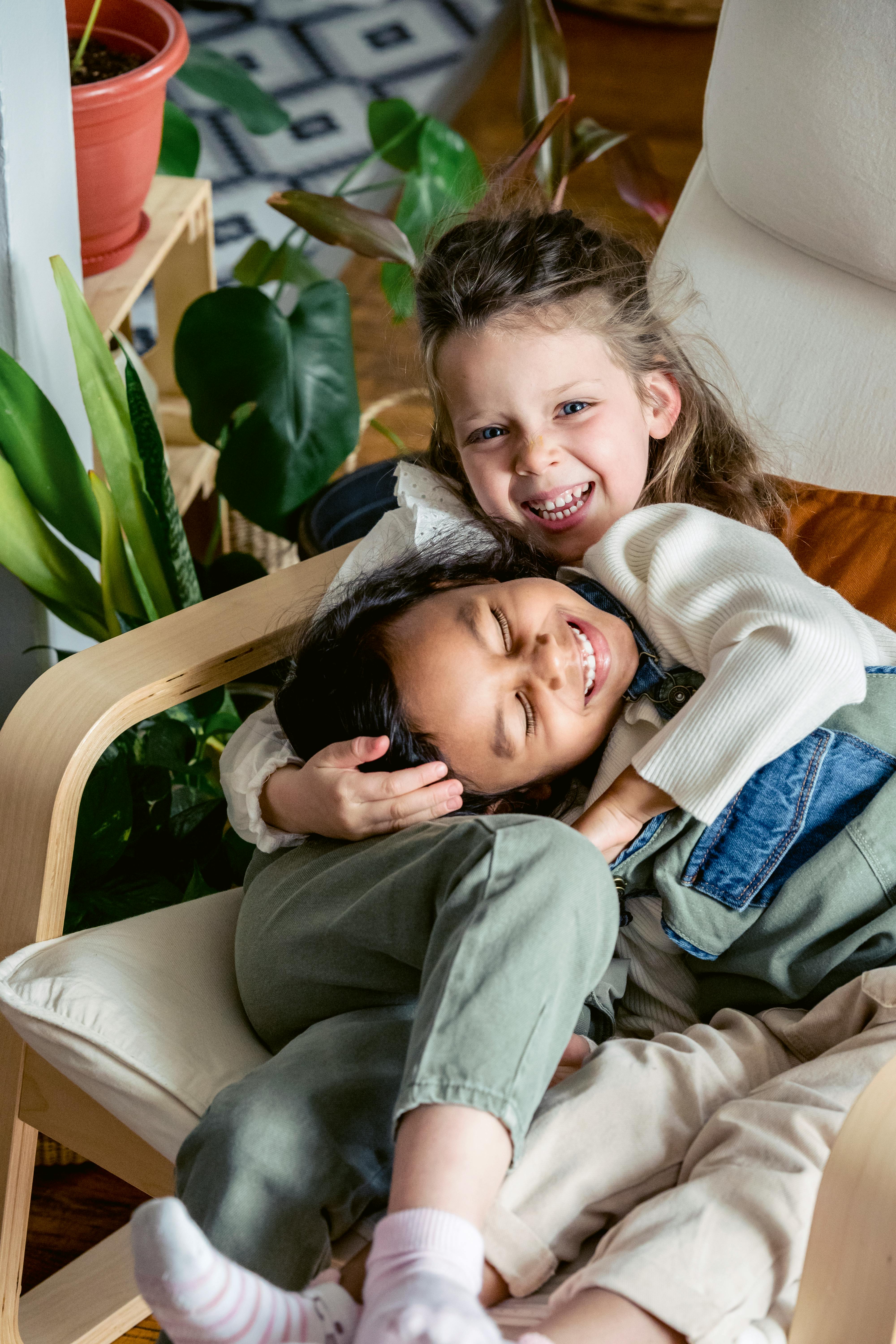 happy diverse kids cuddling in armchair