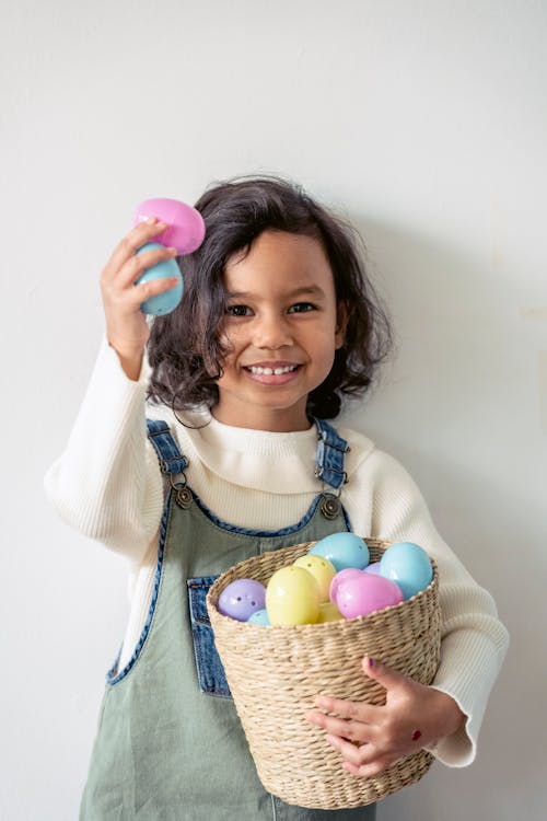 Happy Hispanic girl with multicolored Easter eggs in hand