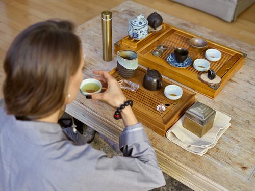 Free Woman enjoying a serene tea ceremony with traditional tea set on wooden table indoors. Stock Photo