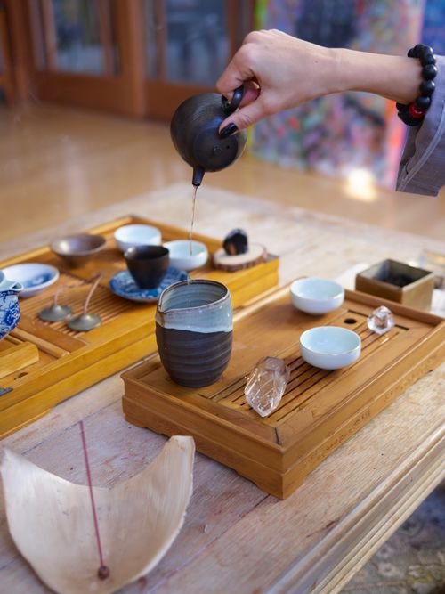 Free A serene indoor tea ceremony setup featuring ceramic cups, incense, and crystals on wooden trays. Stock Photo