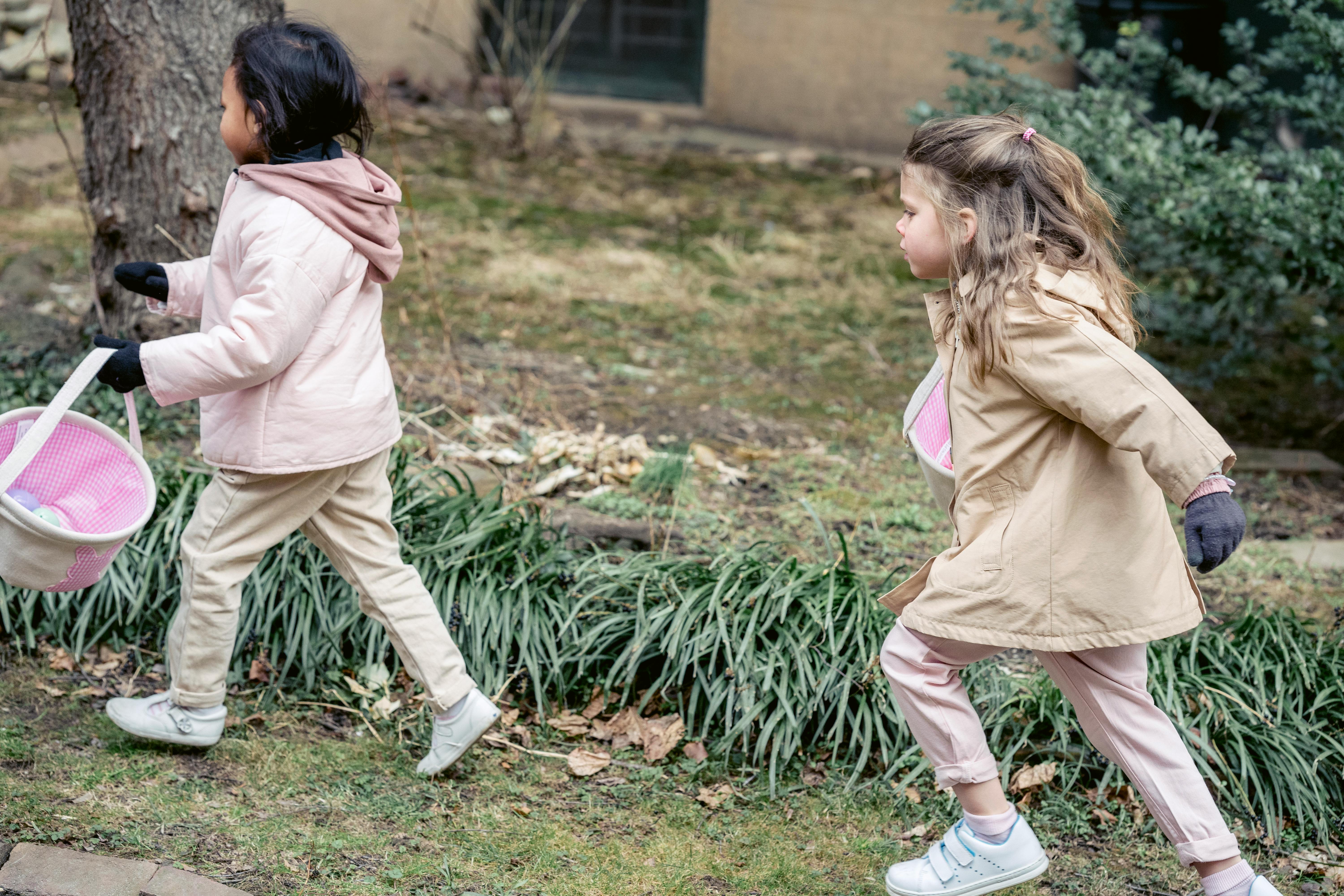 cute girls with soft baskets looking for eggs in spring garden