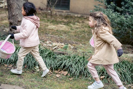 Cute girls in warm clothes and gloves carrying soft baskets during Easter Egg hunt strolling in spring garden