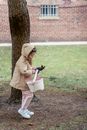 Side view full body girl in warm clothes carrying fabric bag and standing near tree in spring park