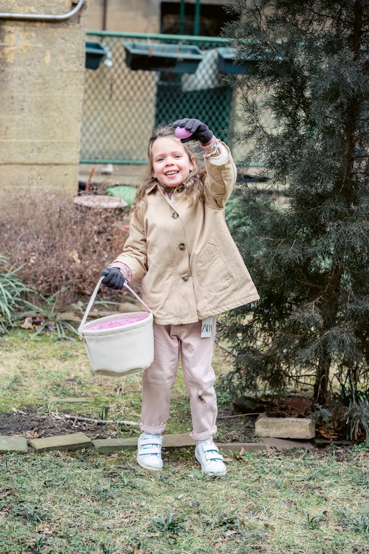 Happy Girl Demonstrating Easter Egg In Spring Garden