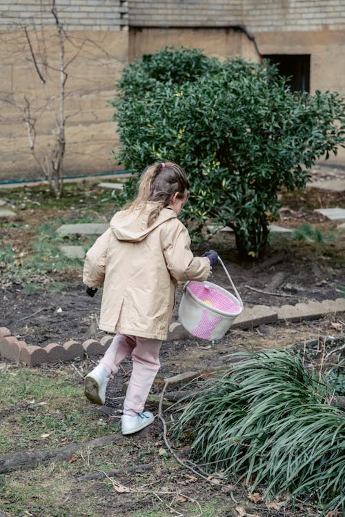 Free Faceless girl collecting Easter eggs in courtyard Stock Photo