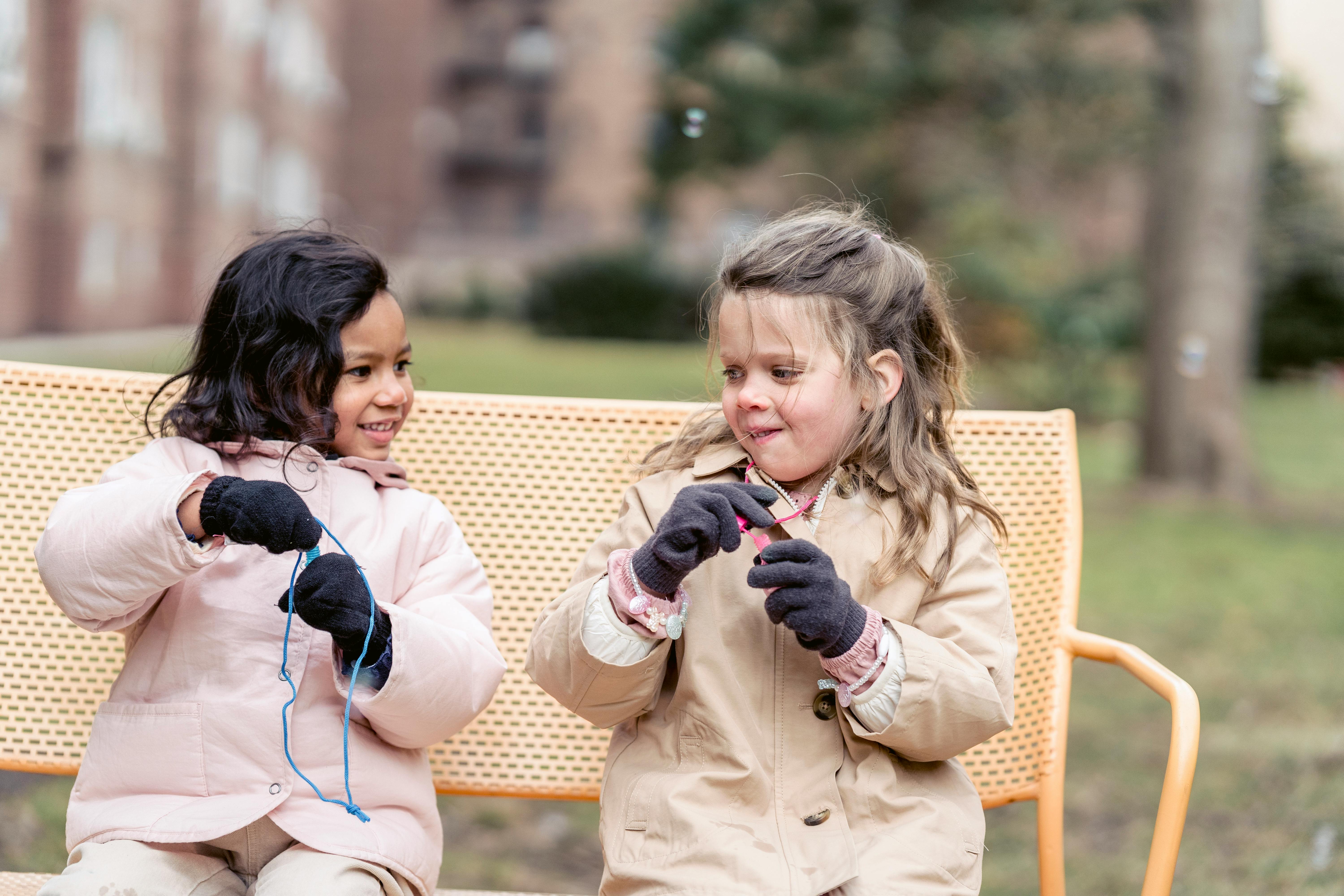 joyful diverse girls playing with soap bubbles in spring park