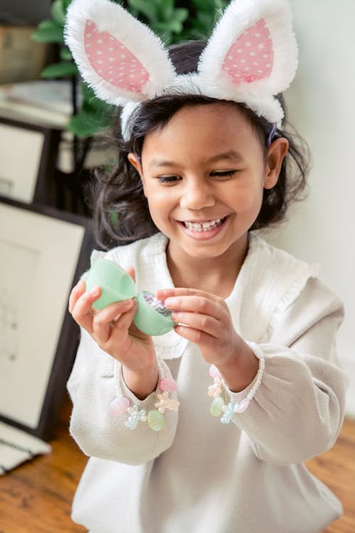 Smiling Hispanic girl with decorative Easter egg at home