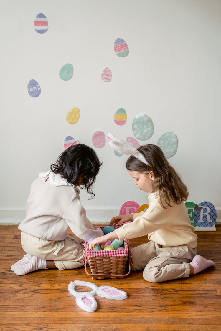 Unrecognizable Diverse Girlfriends With Decorative Easter Eggs On Parquet