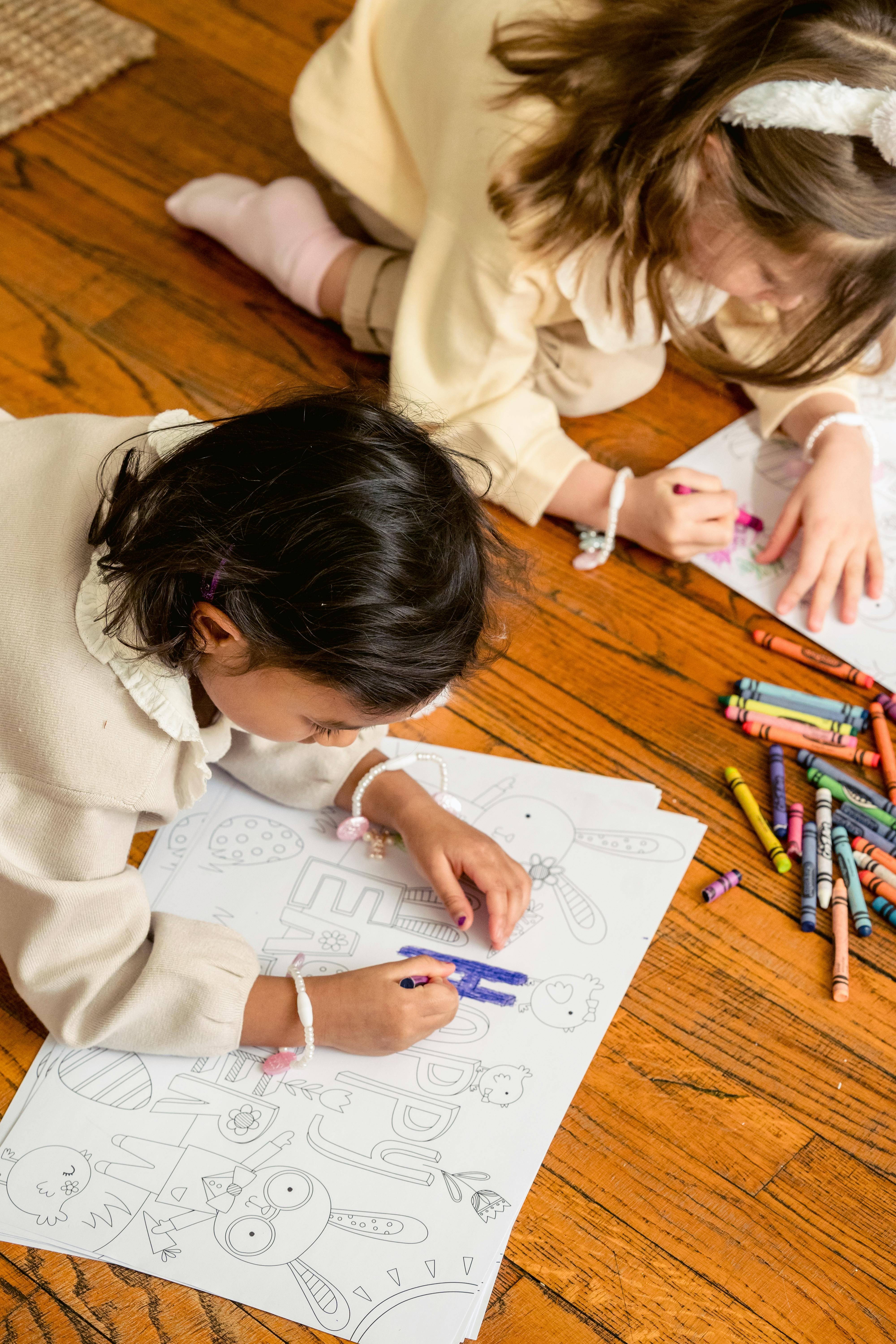 crop attentive multiethnic girls coloring drawings on easter holiday