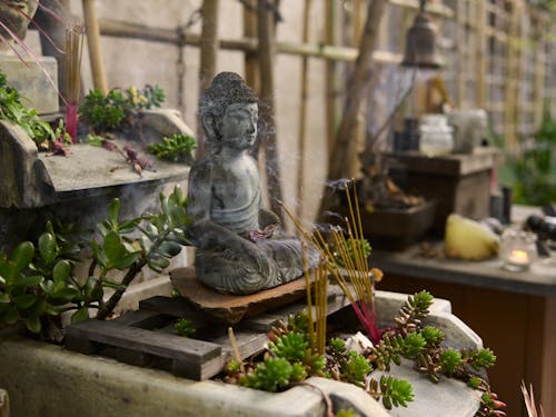Gray Ceramic Buddha Figurine with Lighted Incense Sticks