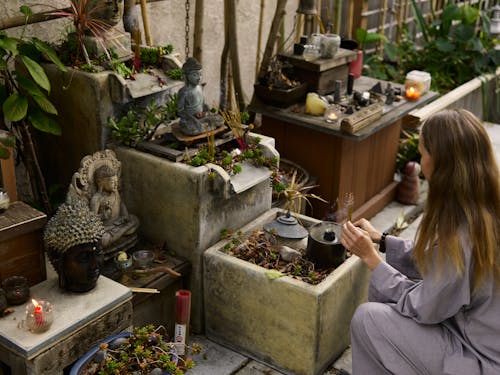 Woman Placing Incense Sticks on a Buddha Shrine