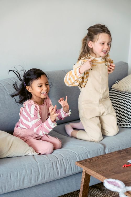 Girls Wearing Pink and Yellow Jumper Sitting on the Sofa · Free Stock Photo