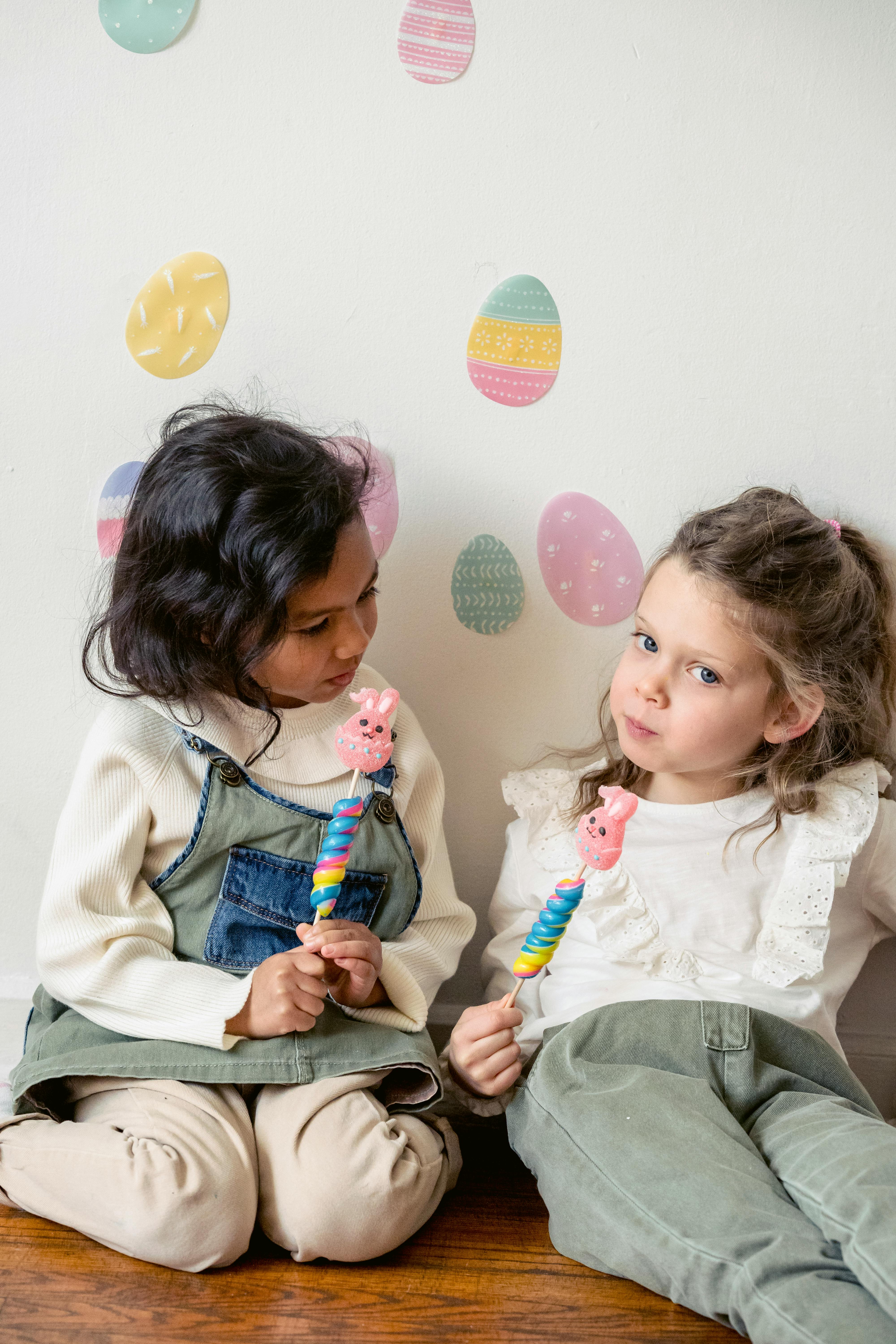 charming multiethnic girlfriends with easter candies on floor at home