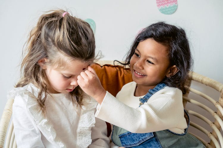 Hispanic Girl Playing With Friend On Sofa