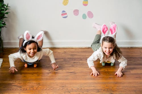 Free Diverse preschool girls having fun while riding on floor with toy rabbit ears Stock Photo
