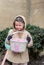 Adorable girl in coat holding textile basket for egg hunt